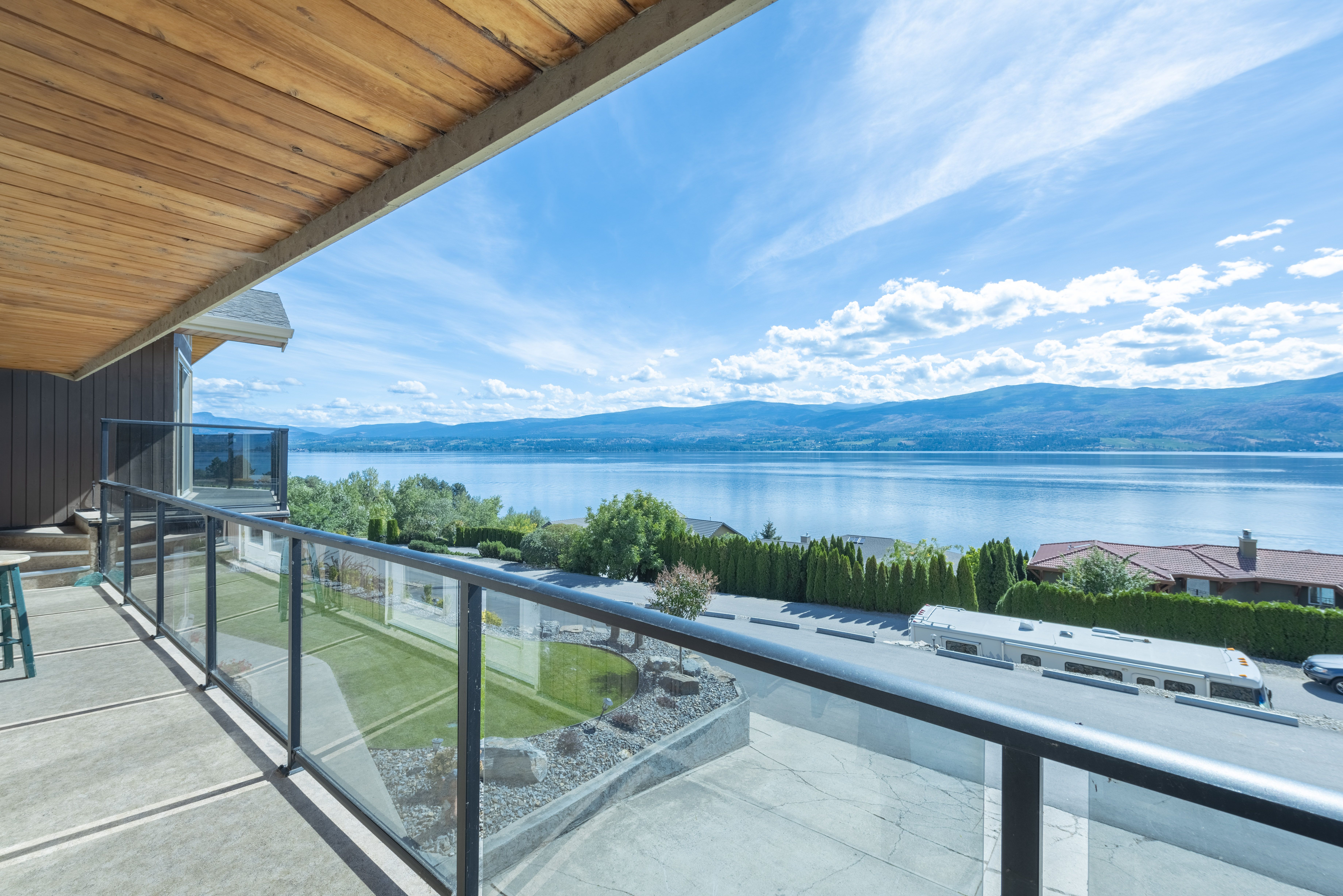 Balcony with glass railing overlooking Okanagan Lake and mountain panorama