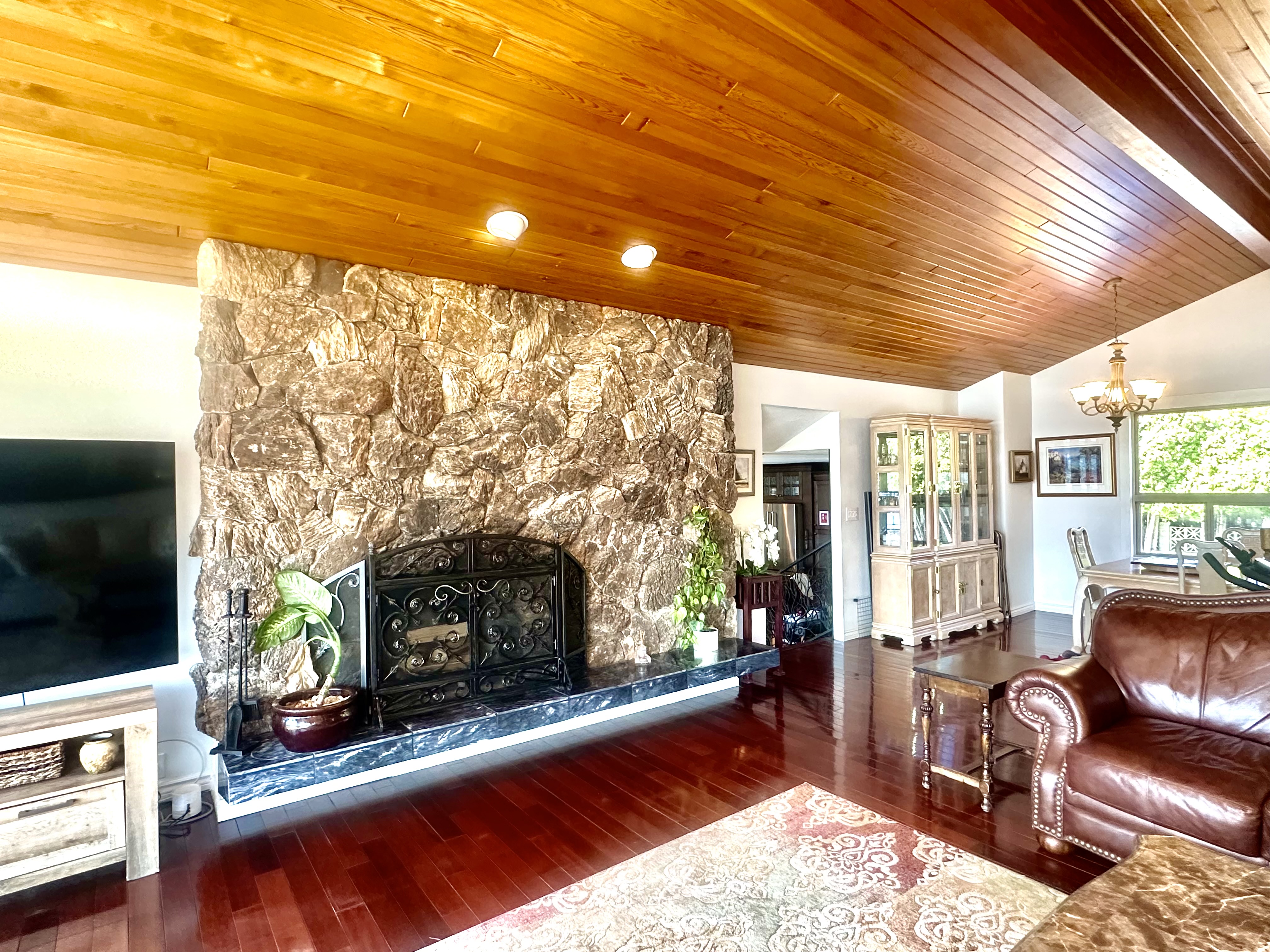 Vaulted living room with stone fireplace, wood ceiling and hardwood floors