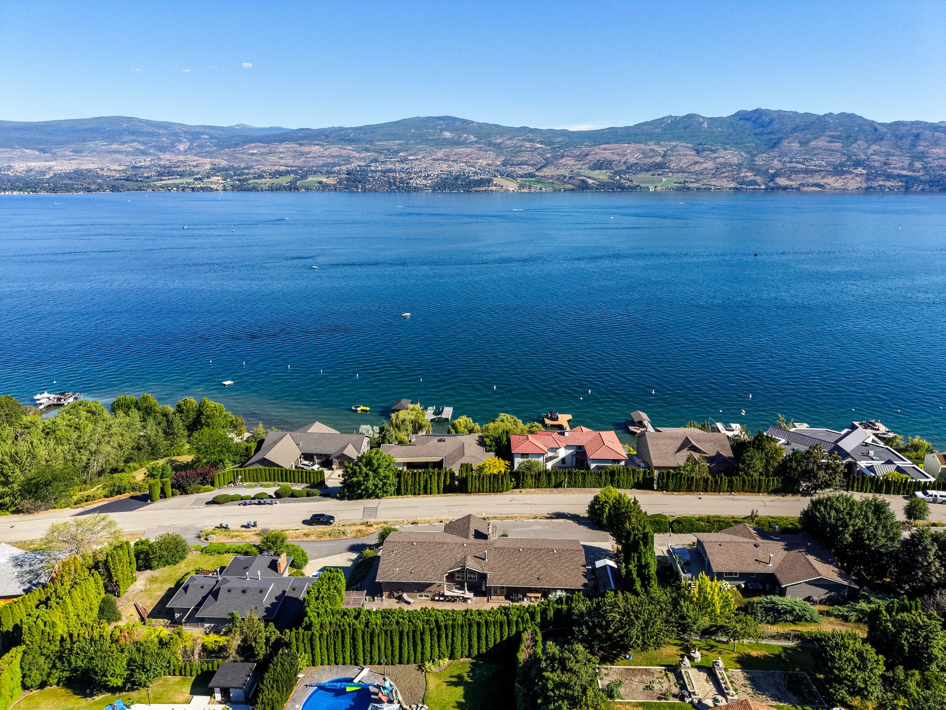 Drone aerial view of Okanagan Lake with boats on the water and mountains beyond