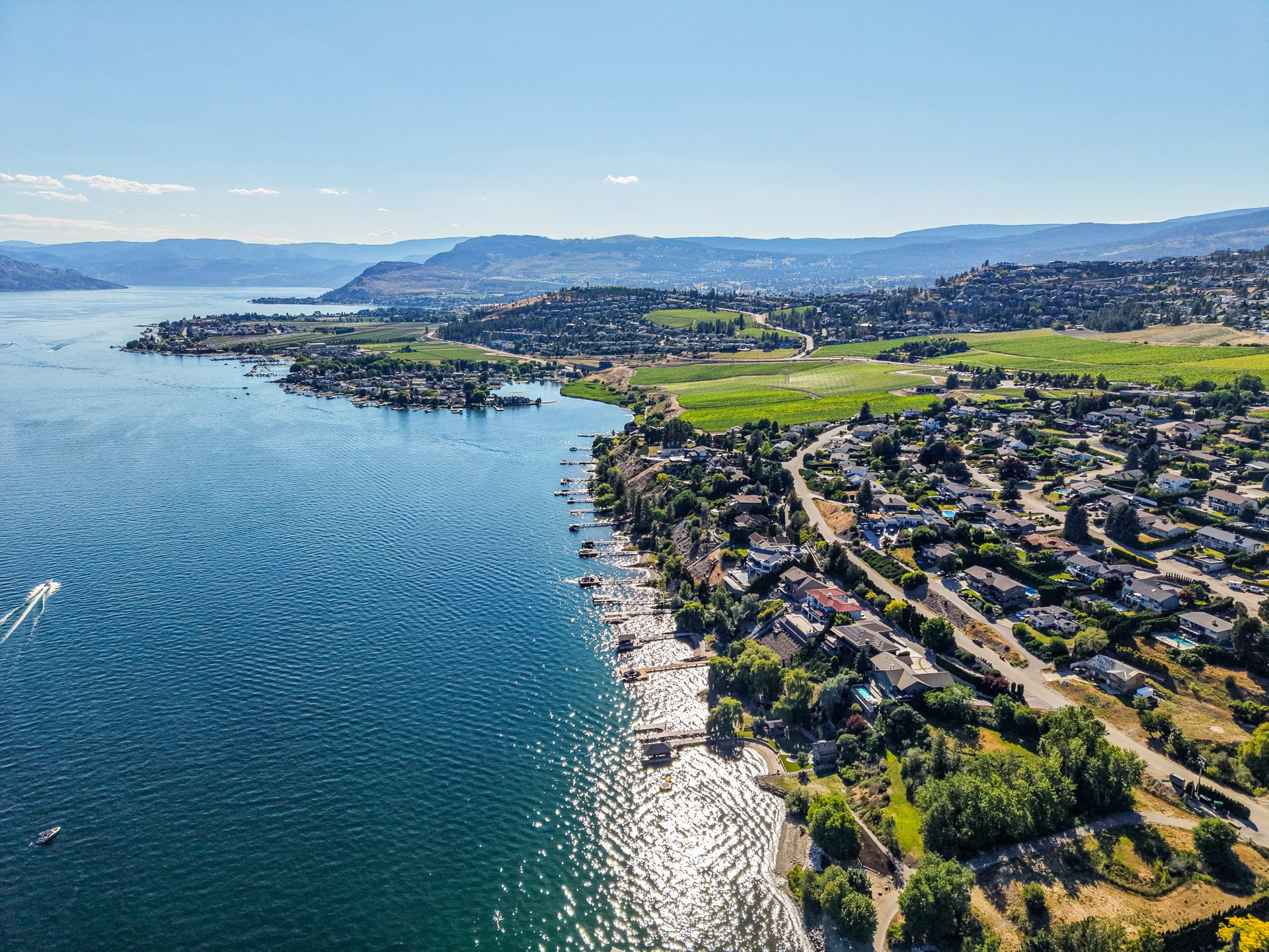 Aerial view of West Kelowna waterfront with docks, vineyards and mountains