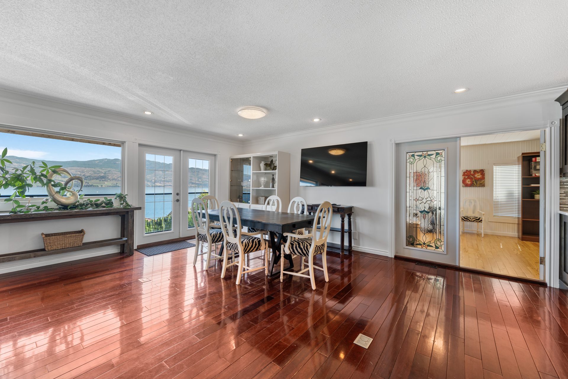 Dining room with cherry hardwood floors, French doors to lake-view balcony and stained glass feature