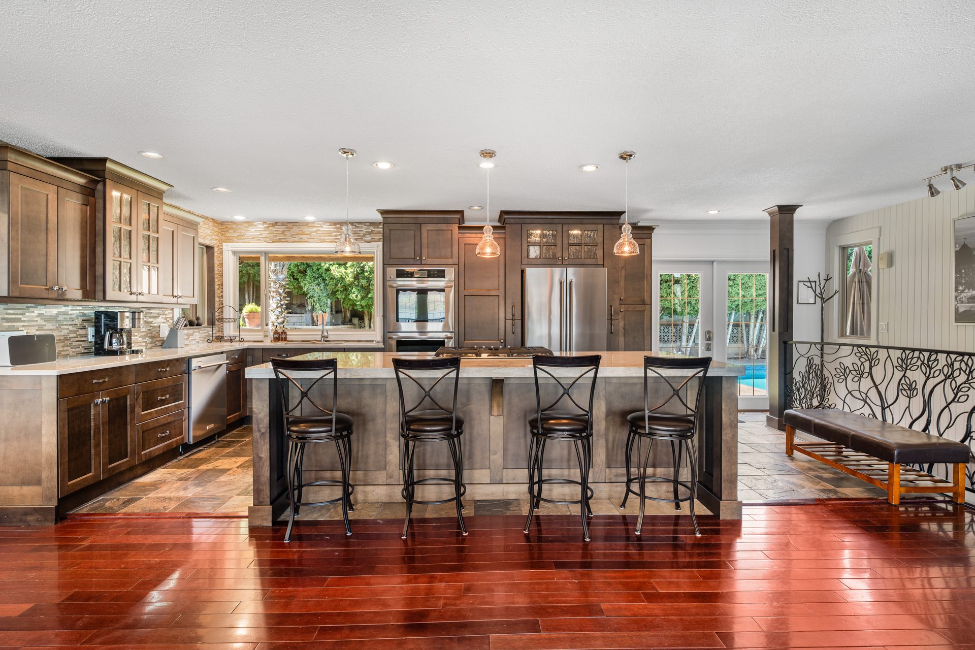 Kitchen with large island, four bar stools, stainless appliances and view to pool