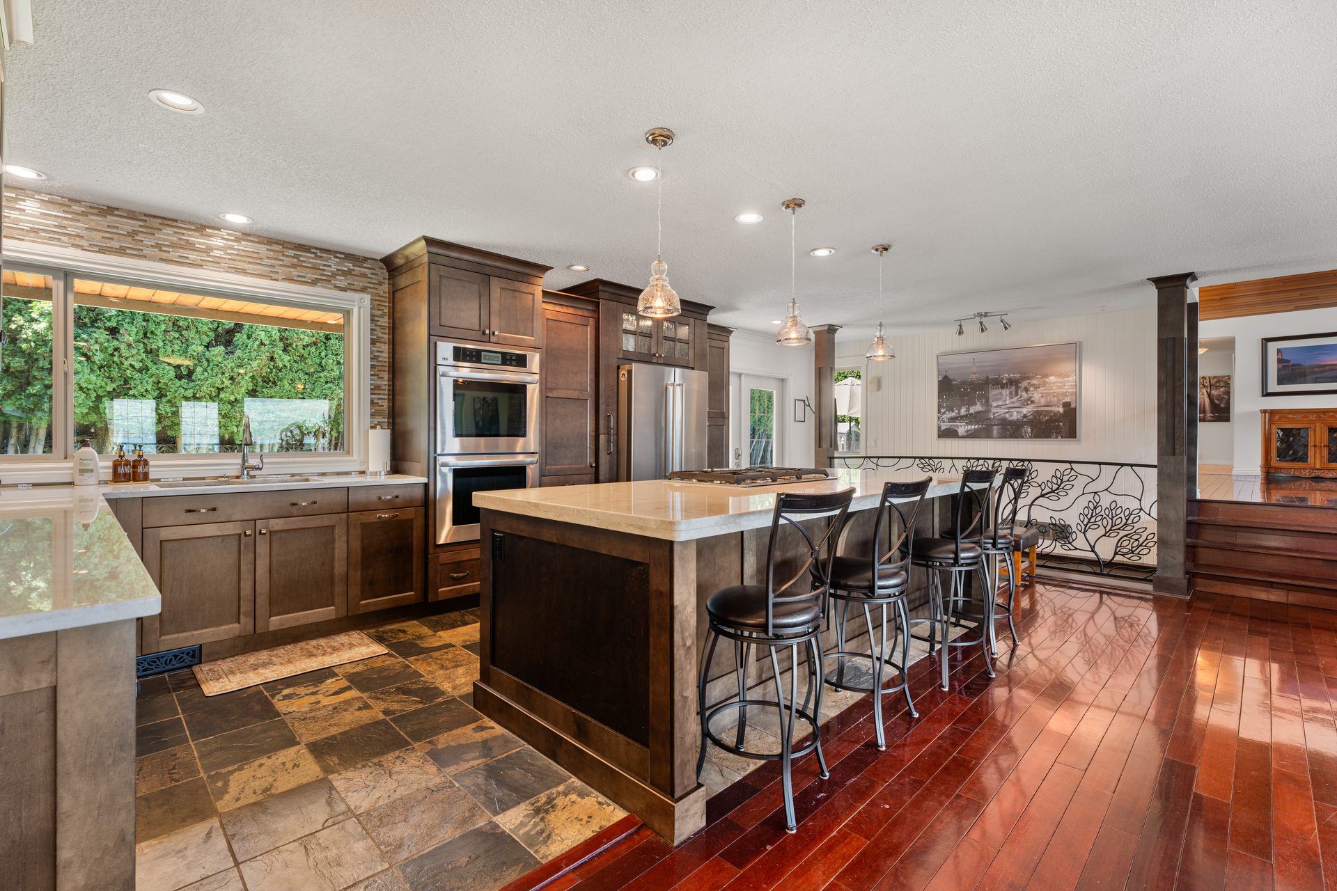 Kitchen detail with double ovens, stainless refrigerator, stone tile backsplash and garden window