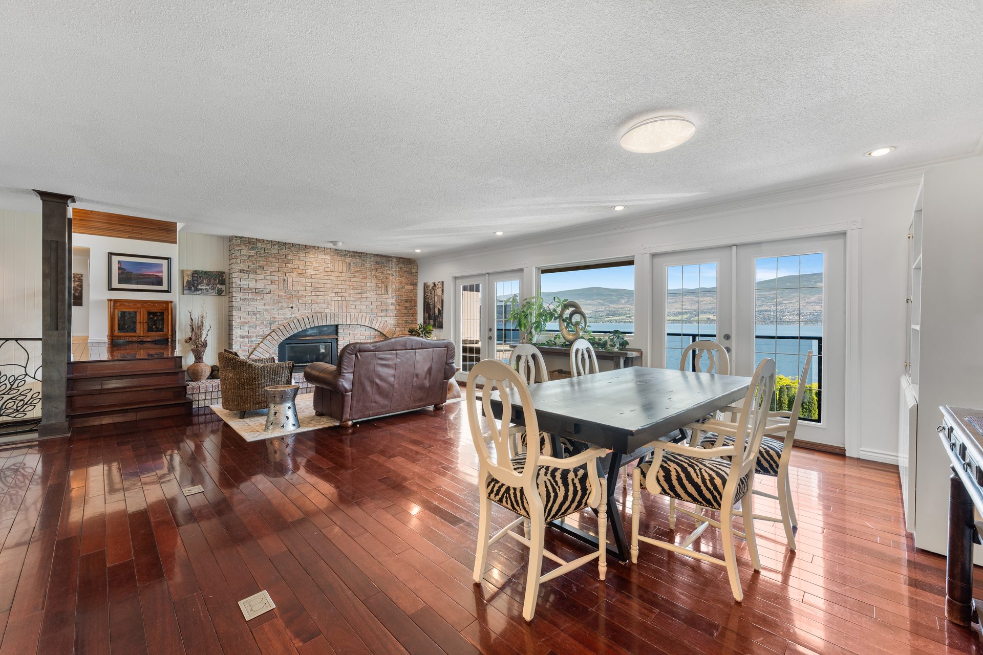 Lower living room with floor-to-ceiling brick fireplace and open plan view to dining and balcony