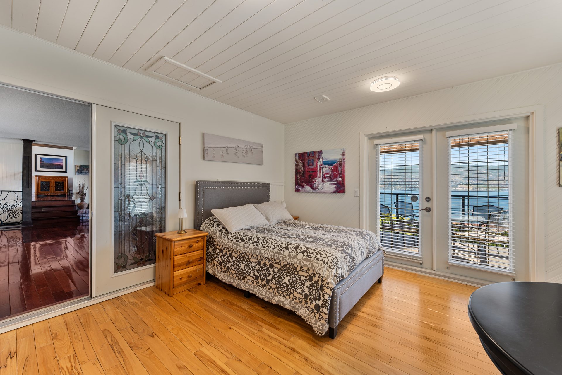 Queen bedroom with lake view French doors, stained glass feature and hardwood floors