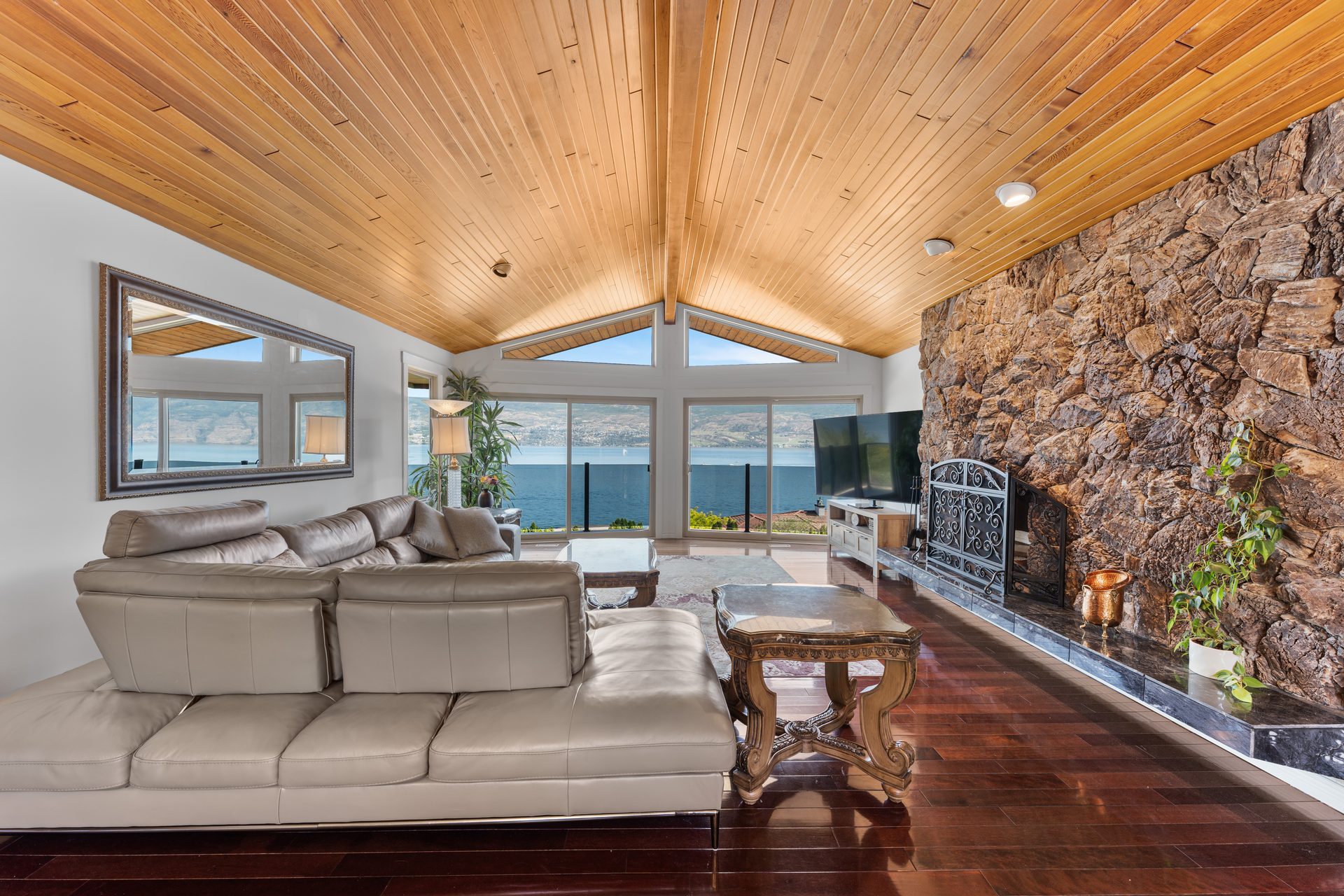 Vaulted great room with stone fireplace, panoramic Okanagan Lake view and wood ceiling