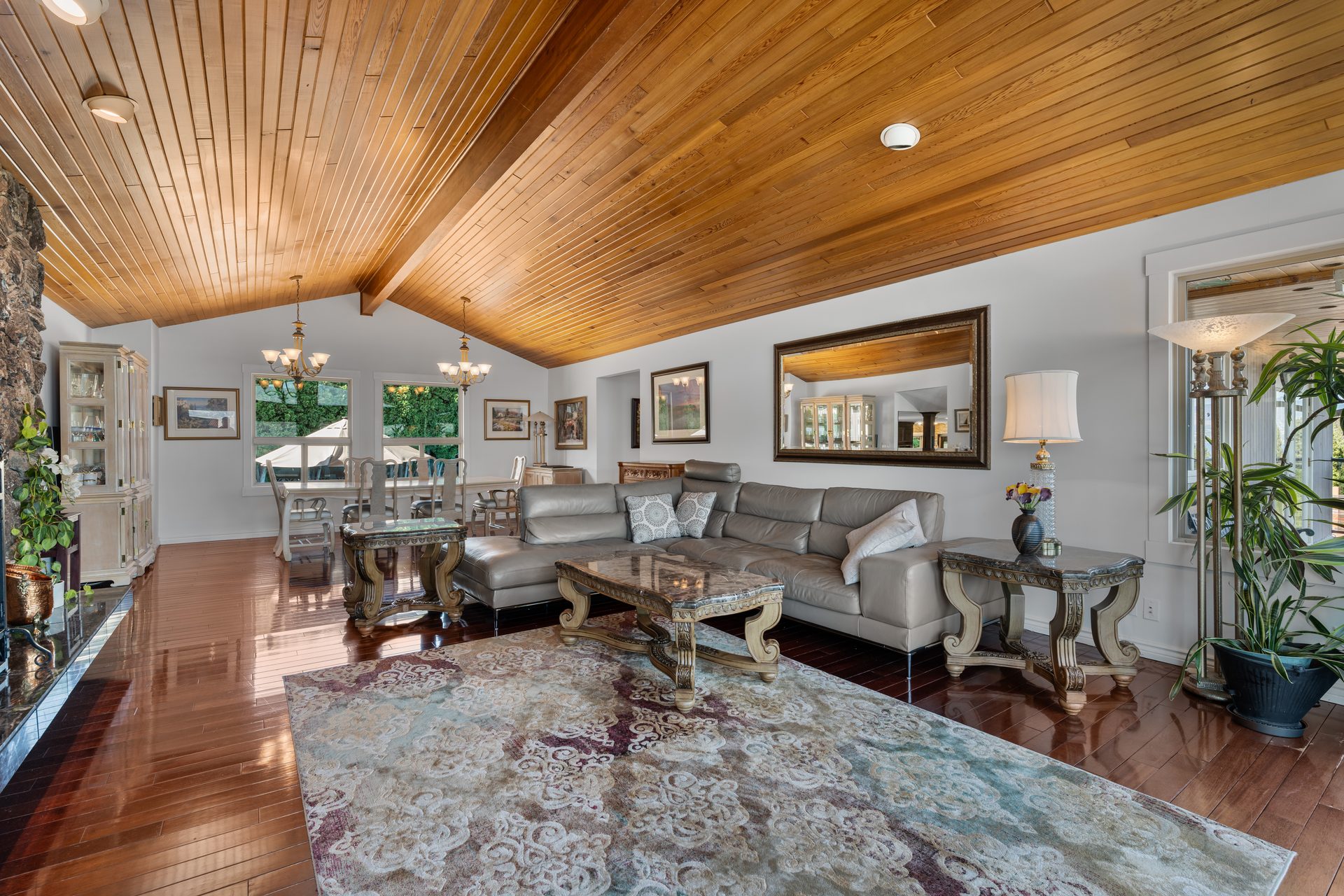 Great room with vaulted cedar ceiling, stone fireplace wall, grey sectional and lake view