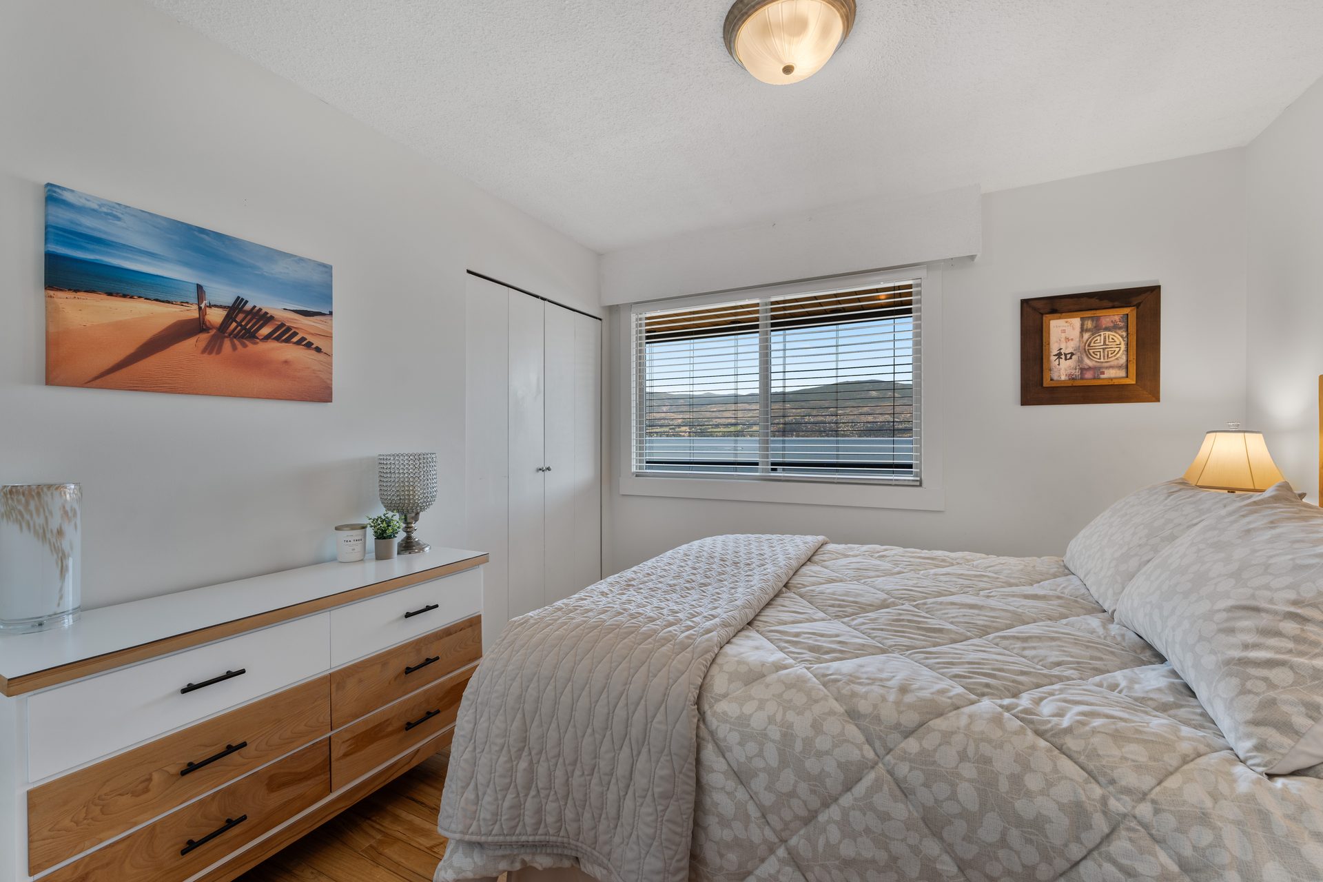 Queen bedroom with mountain view window, dresser and ceiling fan