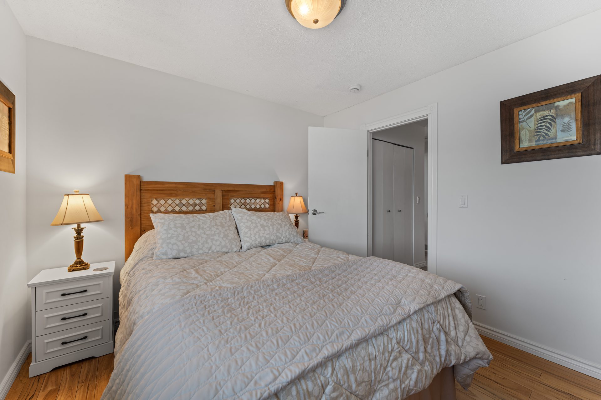 Queen bedroom with wood headboard, twin nightstands and lake view window