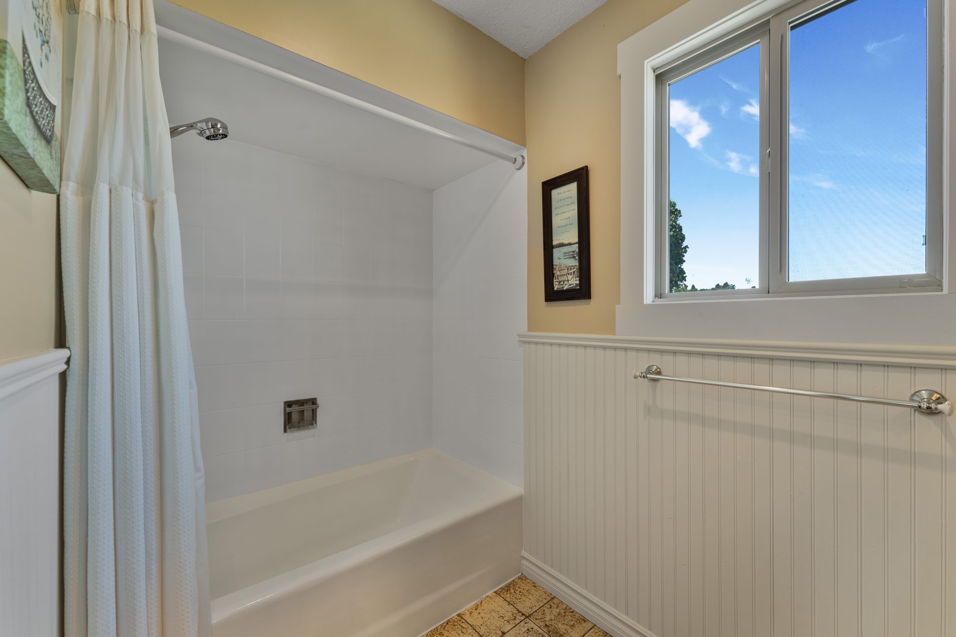 Bathroom with tub and shower, beadboard wainscoting and natural light window