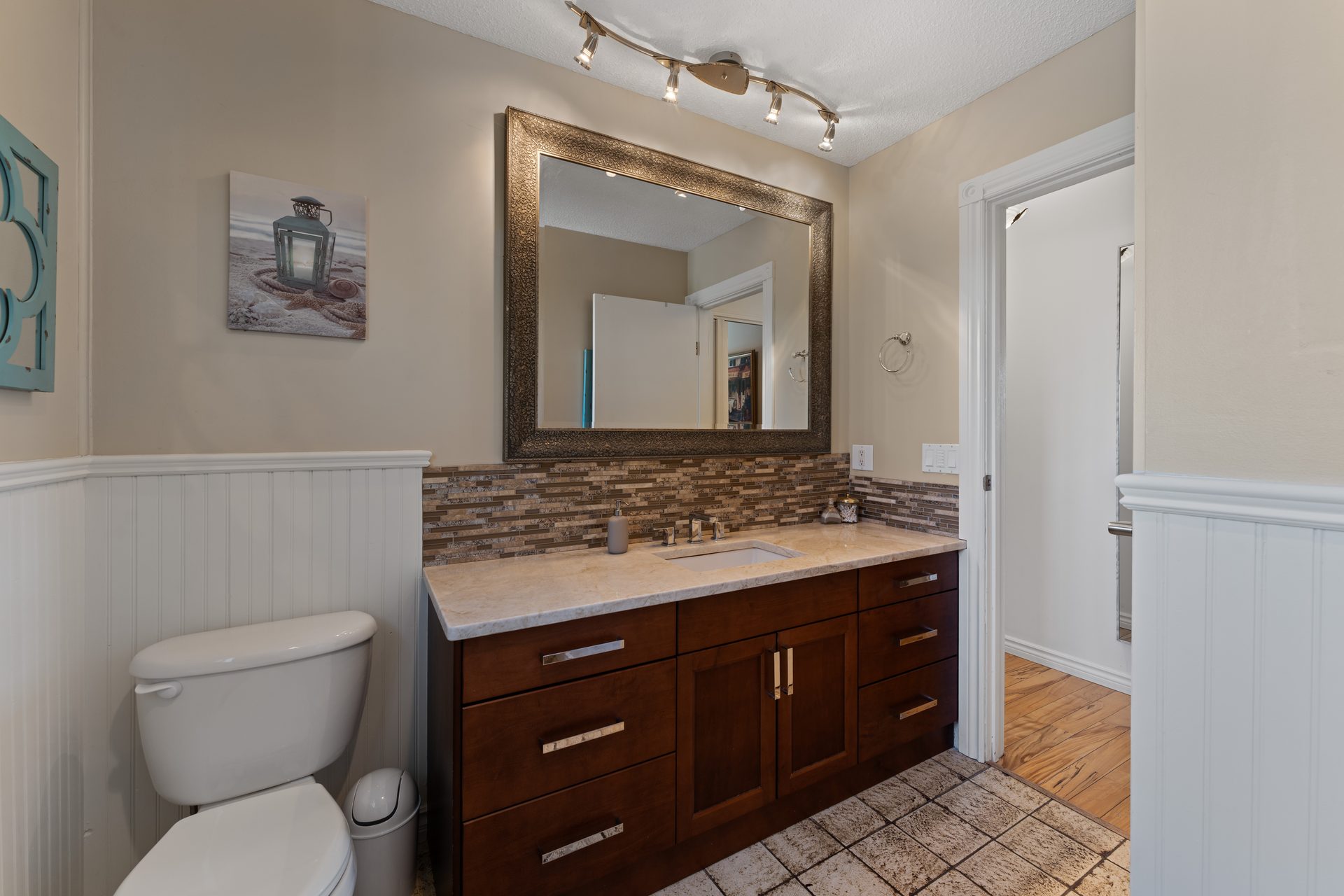 Bathroom vanity with stone mosaic backsplash, large mirror and dark wood cabinetry