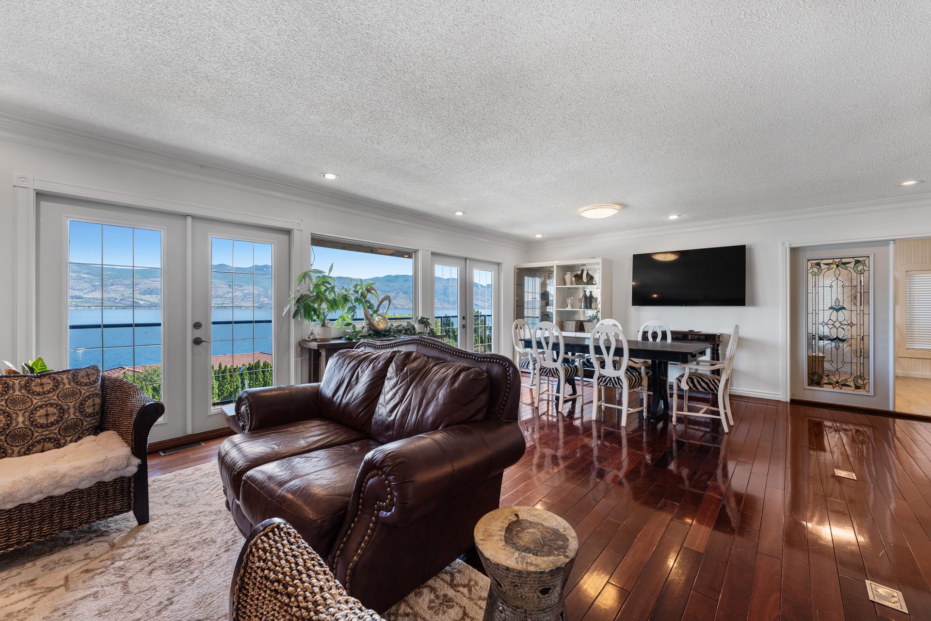 Open-plan living and dining area with lake views through French doors and cherry hardwood floors