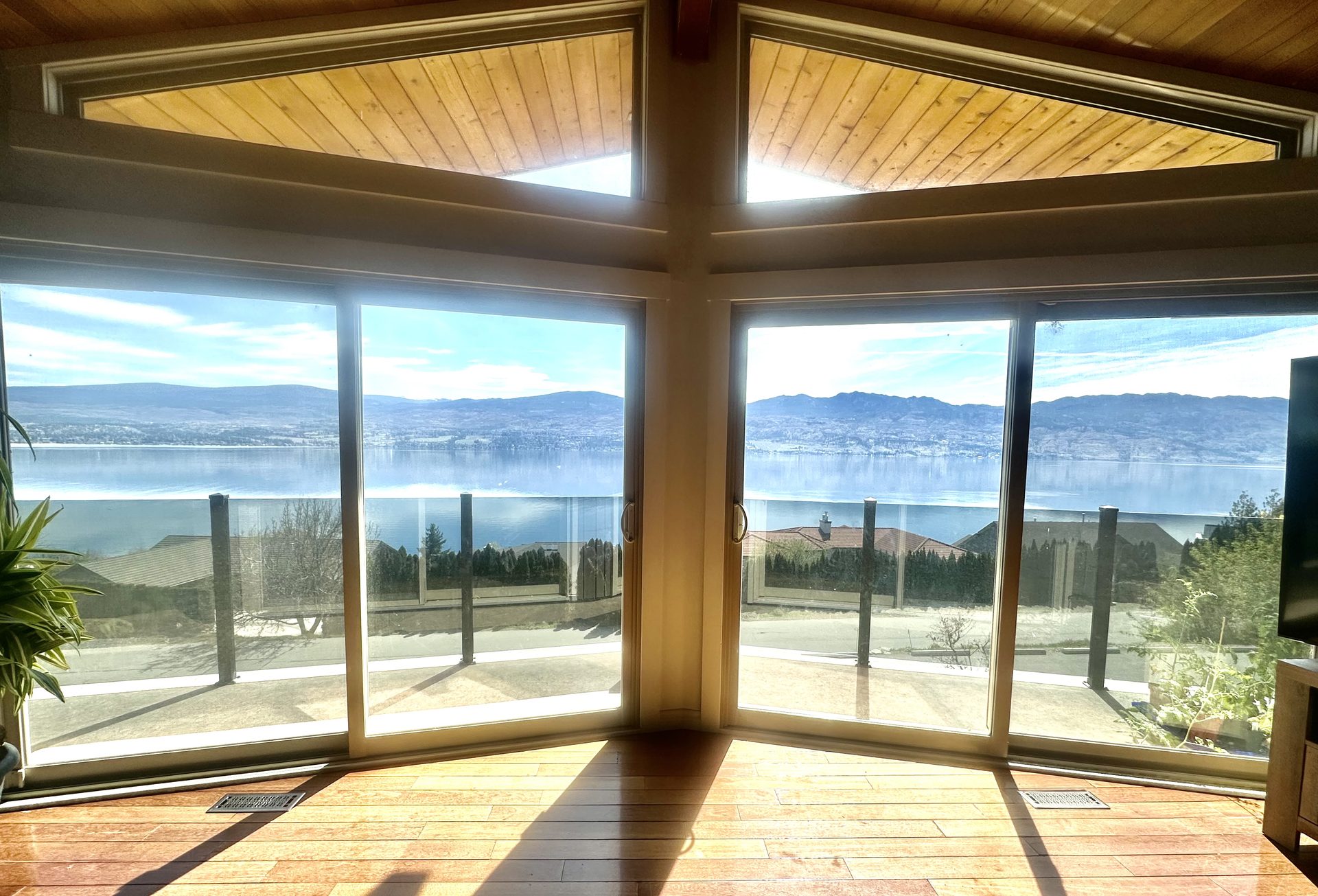 Floor-to-ceiling great room windows framing panoramic Okanagan Lake and mountain view